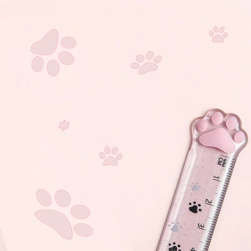 A plastic ruler marked with paw prints is shown against a pink background.