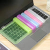 A laptop keyboard is shown with multiple colored silicone keyboard covers, including green, purple, blue, and pink.