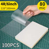 A hand holds a clear thermal laminating pouch, showing its size and material against a grid background.
