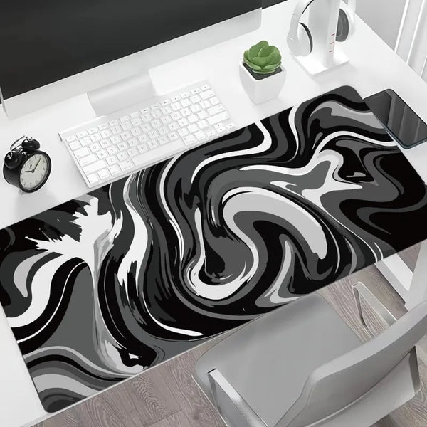 A large gaming mouse pad featuring a black and white liquid wave design placed on a desk.