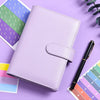 A purple A6 budget planner with a leather cover and envelope system resting on a purple surface.
