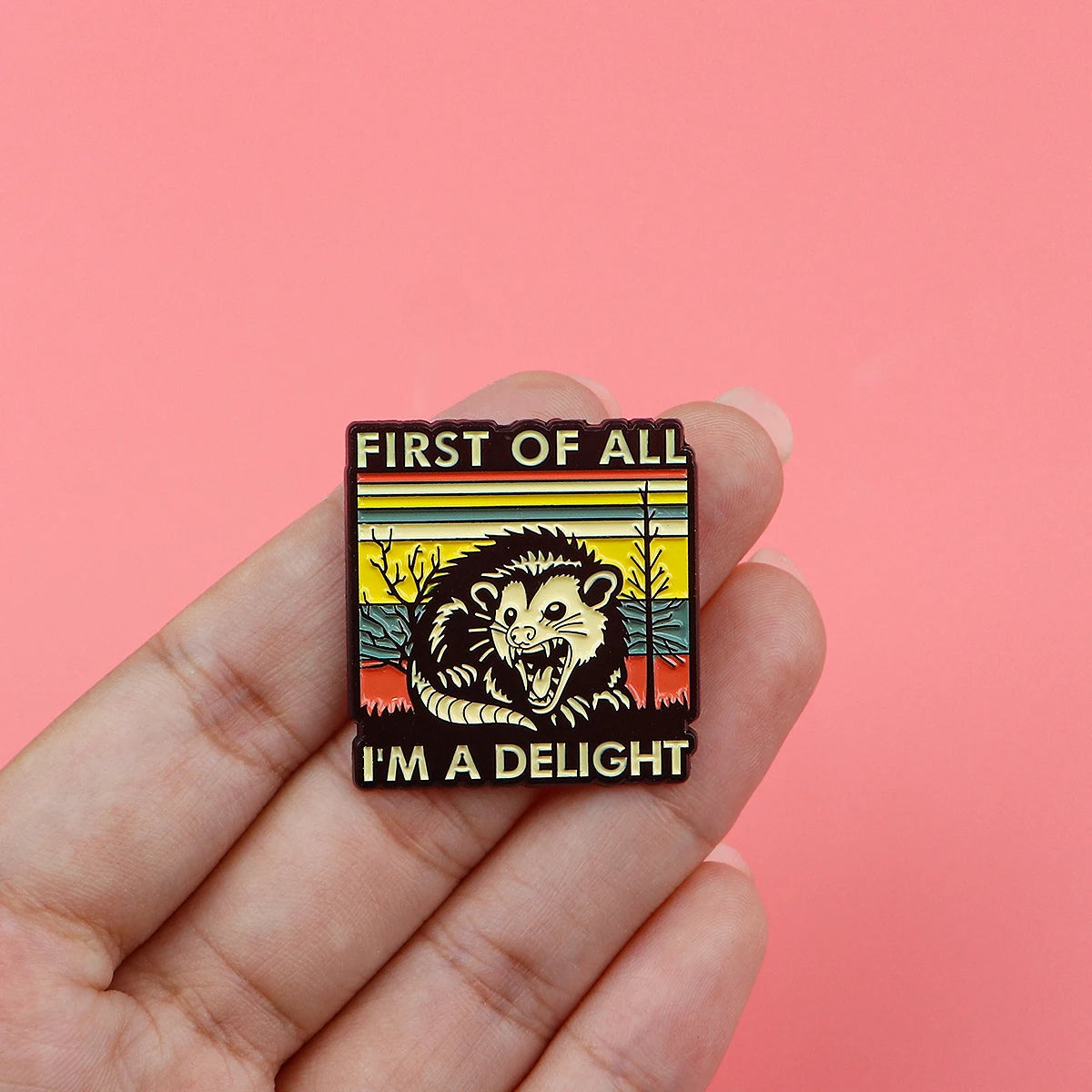 Broche émail représentant un visage d'animal stylisé et féroce avec le texte : First of All I'm a delight.