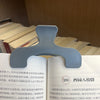 A close-up of a light gray book page clip used to hold open a transparent book page.