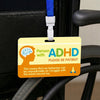 A yellow awareness card for people with ADHD attached to a black wheelchair handle.