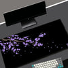 A black gaming mouse pad featuring a purple cherry blossom design and a white keyboard.