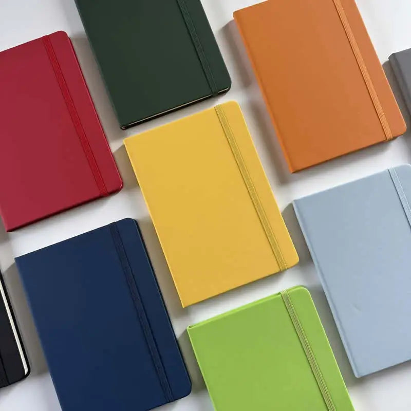 A collection of colorful A5 hardcover lined notebooks in shades of red, green, orange, yellow, blue, and gray.