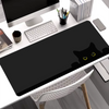 A black cat silhouette mouse pad is placed on a white desk next to a computer monitor and keyboard.