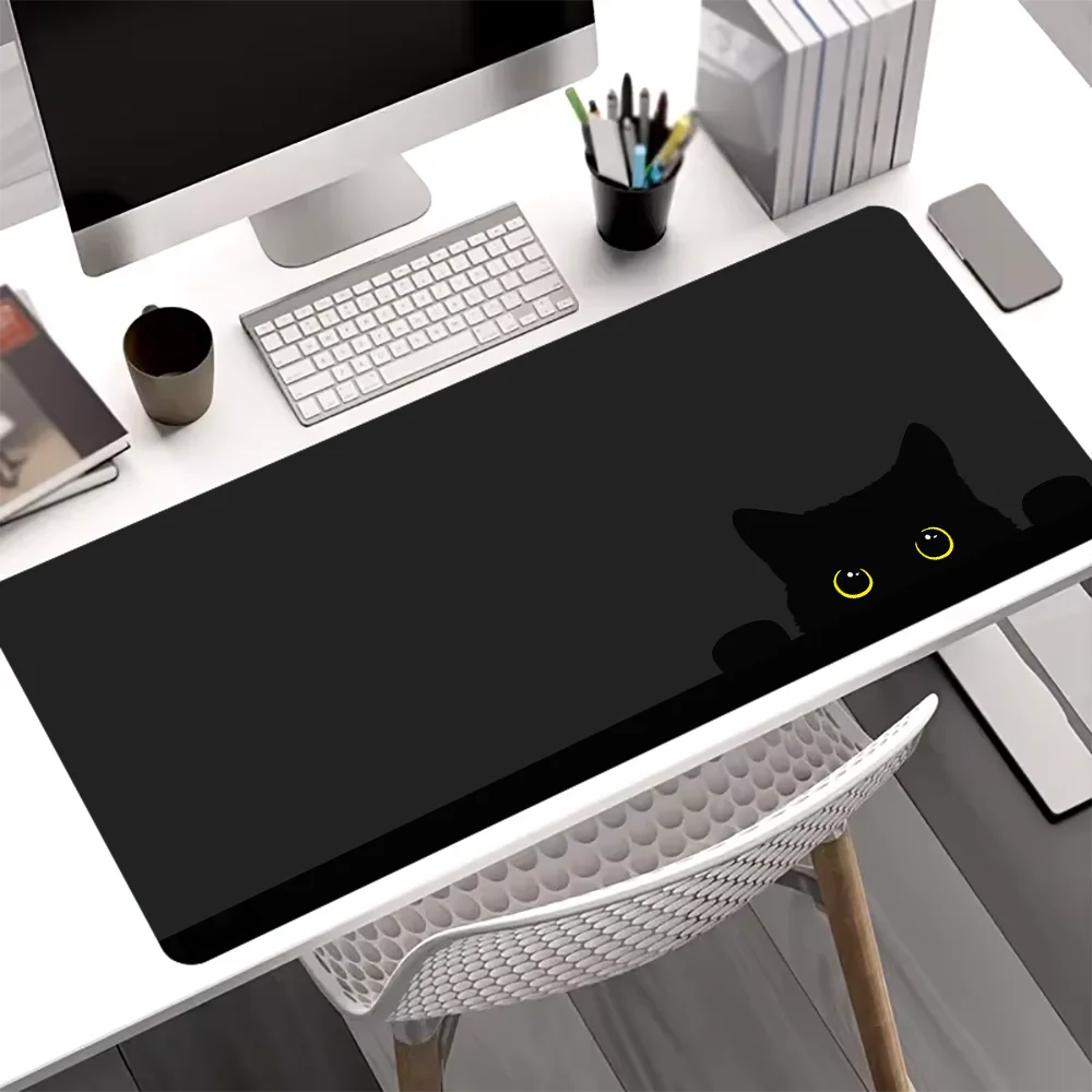 A black cat silhouette mouse pad is placed on a white desk next to a computer monitor and keyboard.