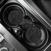 Close-up view of two leopard print non-slip leather car cup holder coasters in a dark interior setting.