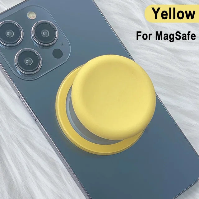 Yellow MagSafe phone grip stand with silicone cover shown on a dark blue smartphone.