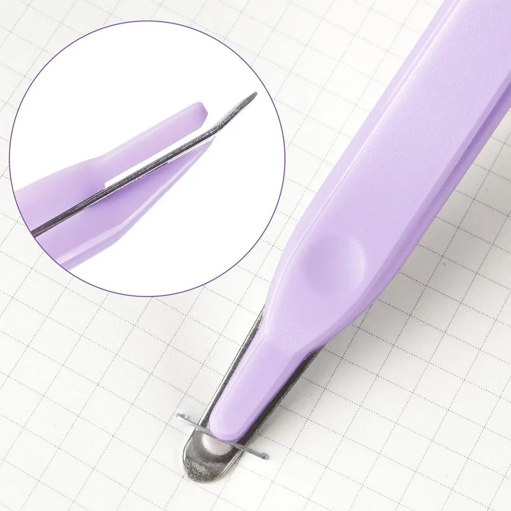 A close-up view of a purple magnetic staple remover tool set on a white grid background.