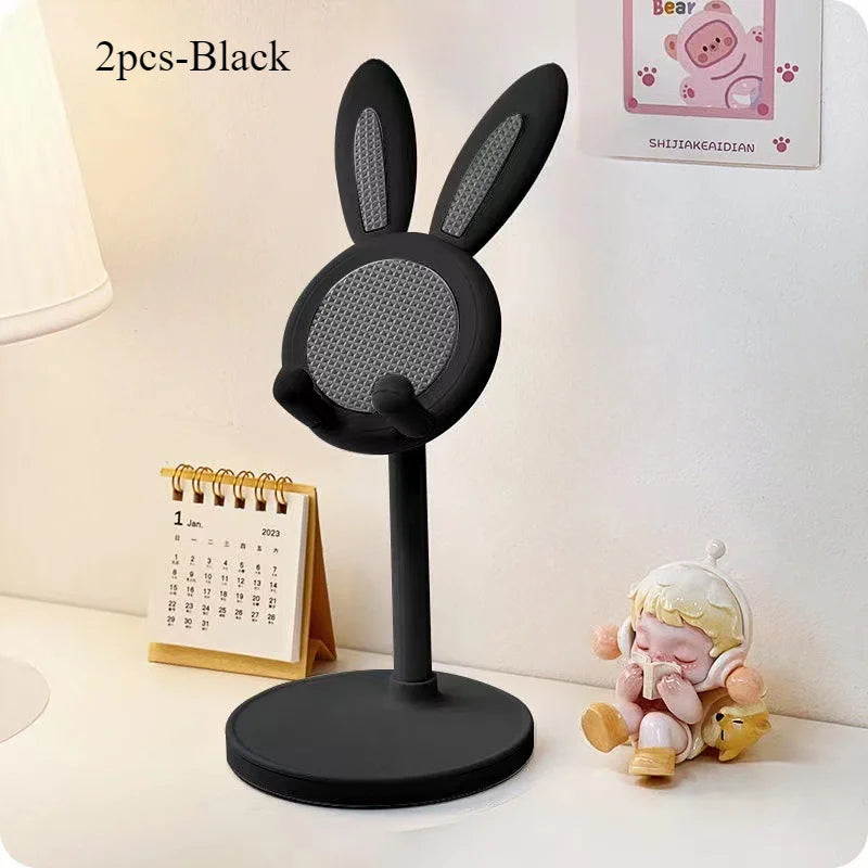 A black rabbit-shaped phone stand with long ears is shown next to a calendar and a small plush toy.