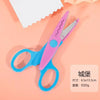 Un par de tijeras de manualidades rosa y azul con diseño ondulado sobre una superficie rosa claro.