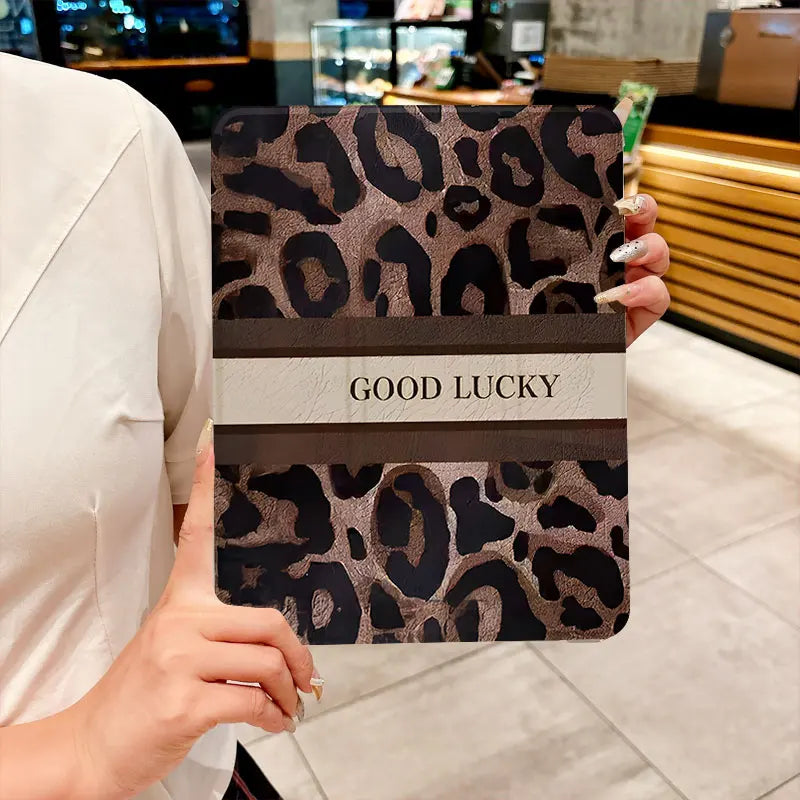 A leopard print protective case for an iPad, featuring a brown and black pattern with the text GOOD LUCKY.