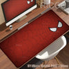 A red Spider-Man themed desk mat featuring a comic book style spider design placed on a wooden desk.