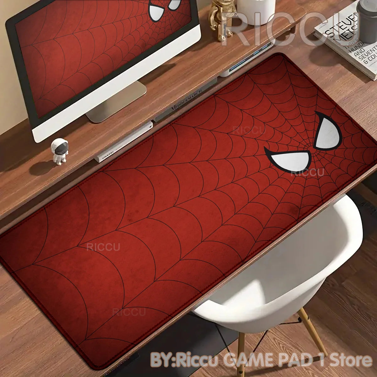 A red Spider-Man themed desk mat featuring a comic book style spider design placed on a wooden desk.
