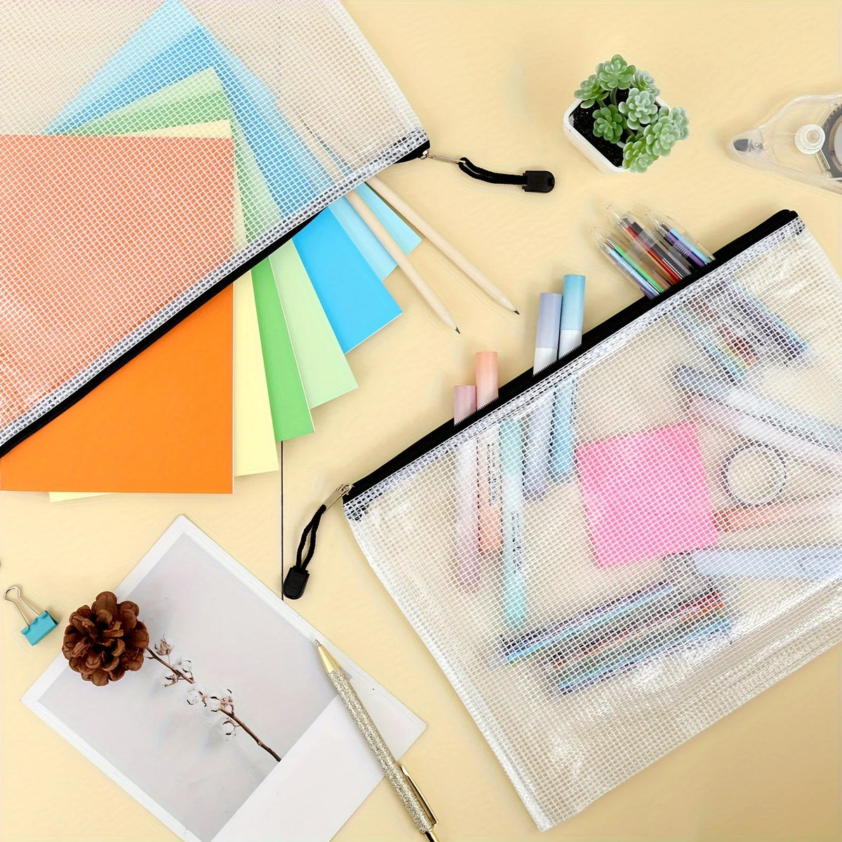 Klare Netztaschen mit Reißverschluss, gefüllt mit verschiedenen Stiften und Schreibwaren auf hellem Hintergrund.