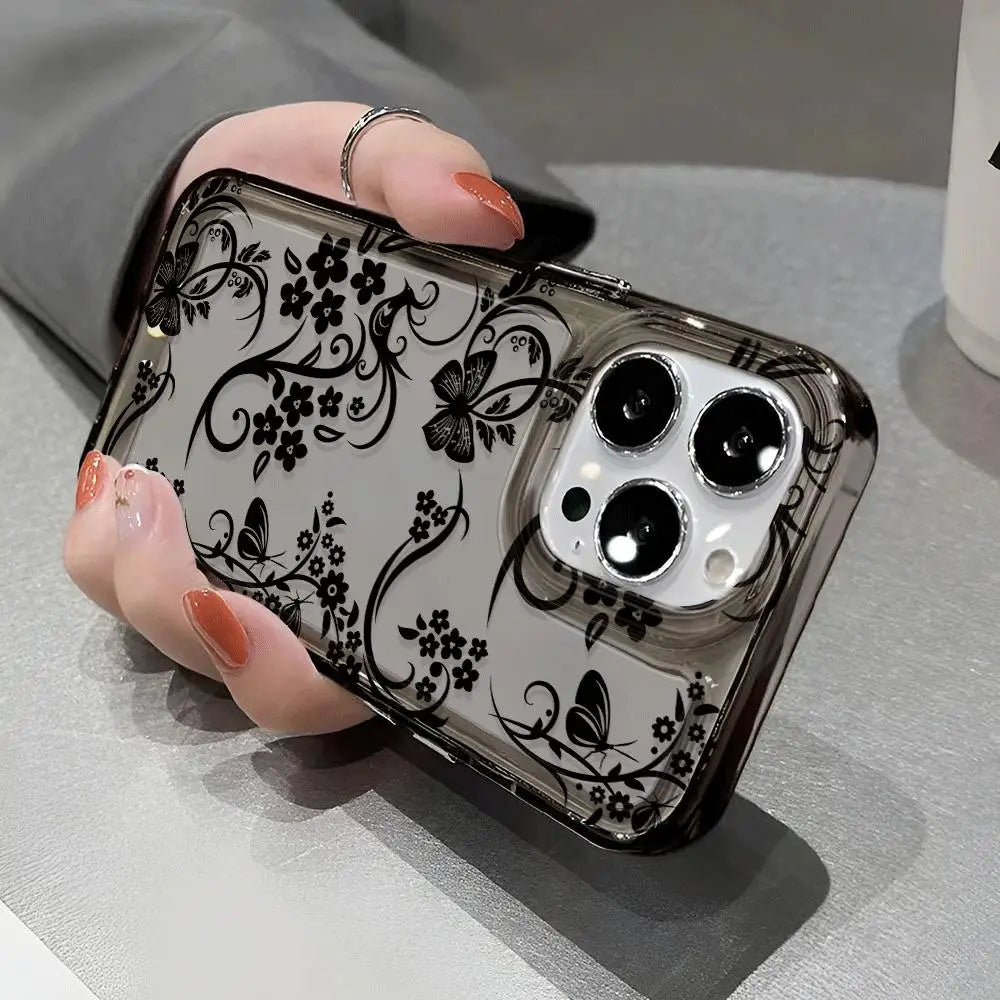 A hand holds a clear phone case with a black floral pattern featuring butterflies and flowers.