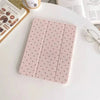 A pink acrylic protective skin with small black dots is displayed on a white table next to an iPad case and eyeglasses.