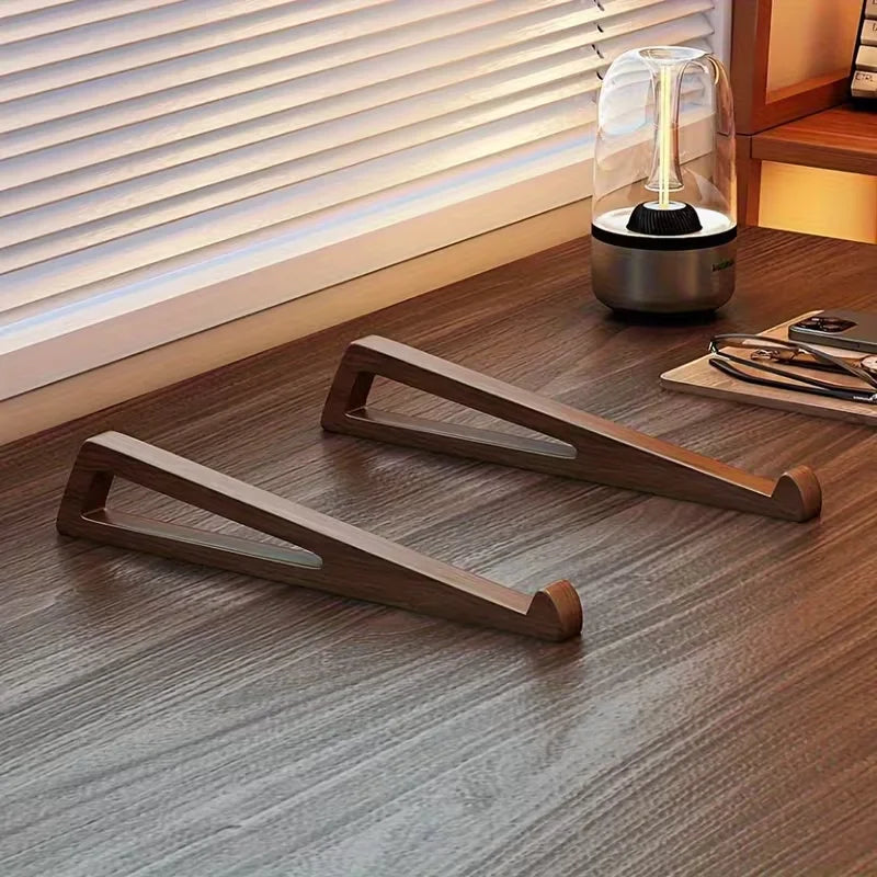 Ein Holz-Laptopständer liegt auf einem dunklen Tisch vor einem lamellierten Fenster.