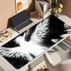 A black and white artistic depiction of an angel wing is displayed on a desk mat.