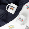 A white mug with an inspirational quote on it is placed on a dark gray fabric background.