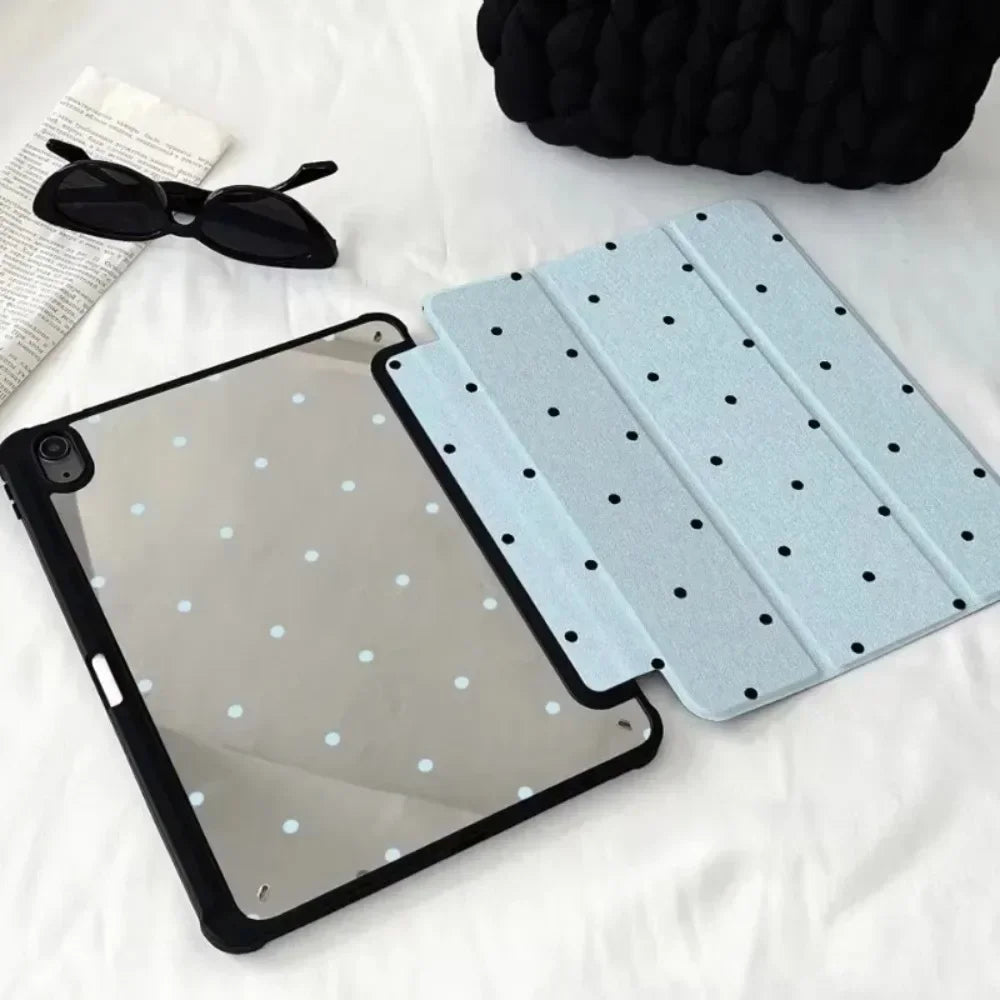 A clear acrylic protective skin for an iPad case is shown next to a pair of sunglasses and a black knitted item.