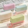 A collection of pink and mint green mini multi-hole punches for notebooks and planners displayed on a white surface.