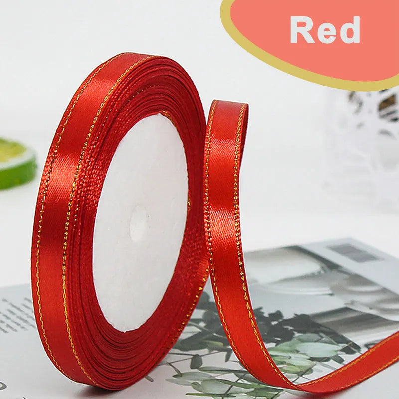 A roll of red satin ribbon with a gold edge is shown next to a piece of paper.