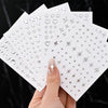 A hand holds a set of metallic 3D star nail art stickers on white cards.