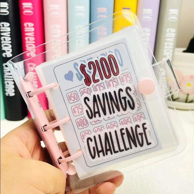 A hand holds a clear binder titled Savings Challenge with dollar amounts and text on the cover.