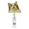 A close-up photo of a cat looking intensely at the camera, positioned above a clear retractable ID badge holder.