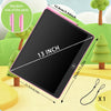 A 13 inch digital writing tablet with a pink stylus and charging cable shown outdoors against a green landscape.