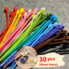 A variety of silicone cable organizers in mixed colors are displayed on a gray surface.