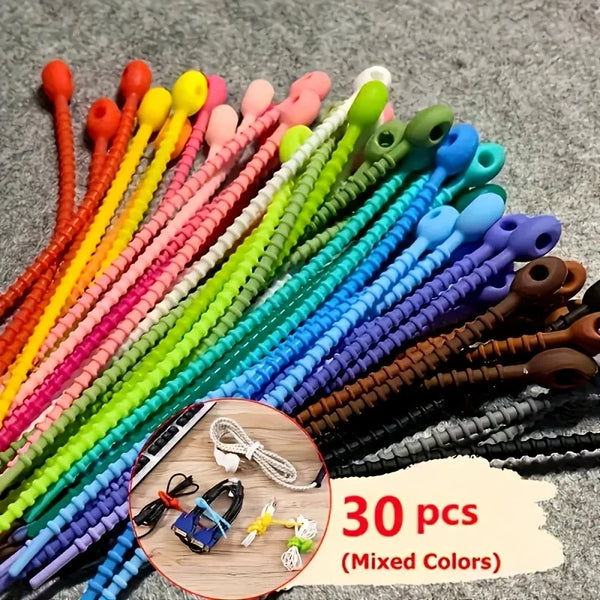 A variety of silicone cable organizers in mixed colors are displayed on a gray surface.