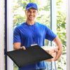 Ein Mann in blauem Hemd und Kappe hält eine schwarze Luftpolsterumschlagbox vor einem Fenster.
