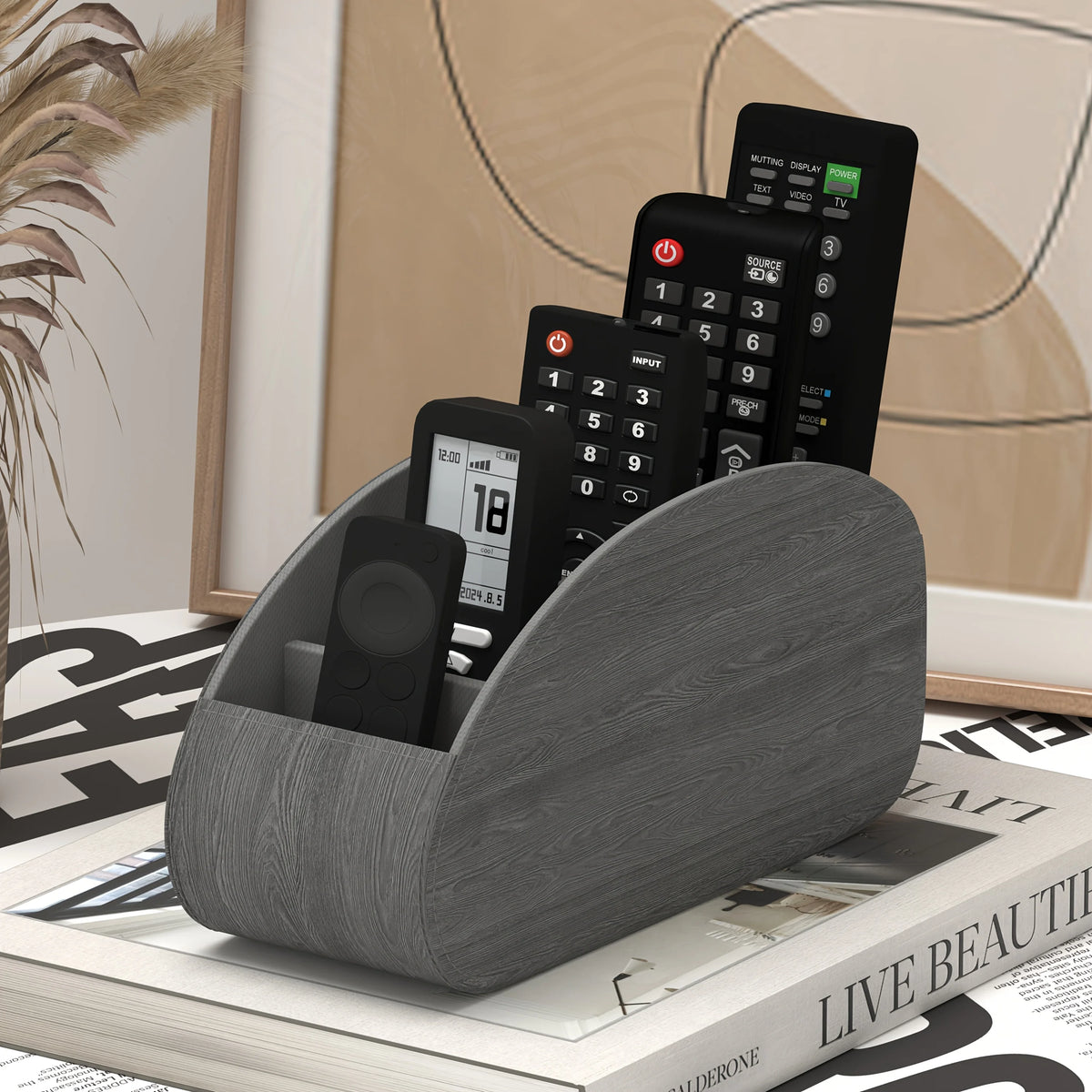 A wooden desk organizer tray holding a black remote control and other electronic devices.
