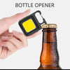 A hand holds a black bottle opener tool next to an amber glass bottle.