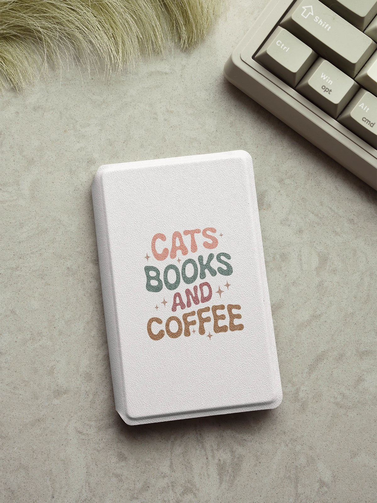 A white magnetic detachable folio cover for an e-reader featuring the text CATS BOOKS AND COFFEE in pink and green lettering.