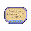 A lapel pin featuring a yellow oval with text "THIS BOOK RUINED MY LIFE. 5 STARS." and five gold stars below.