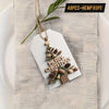 A set of farmhouse Christmas gift tags featuring wood grain and pinecone cutouts tied with hemp rope.