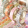 A collection of five rolls of floral washi tape in various pastel colors and patterns displayed next to a box.
