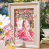 A framed watercolor illustration of a woman surrounded by pink and red floral vines and roses.