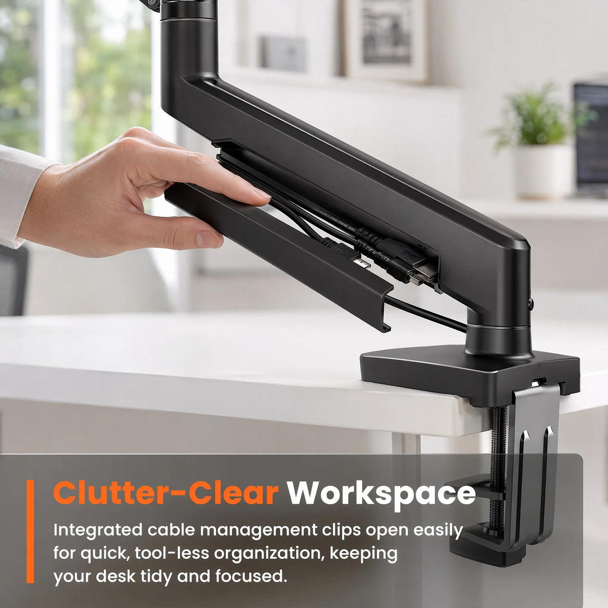 A hand is adjusting a black premium single monitor desk mount with a gas spring arm for tool-less organization.