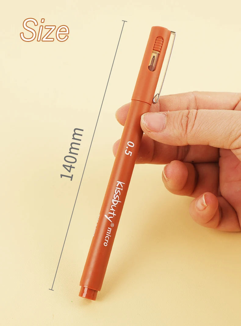 A hand holds an orange micro-pen fineliner with archival ink, demonstrating its size.
