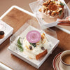 A box of pastel rose thank you stickers roll with a creamy white product displayed on a wooden table.