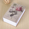 A small notebook with pressed flowers and handwritten text is shown on a wooden surface.