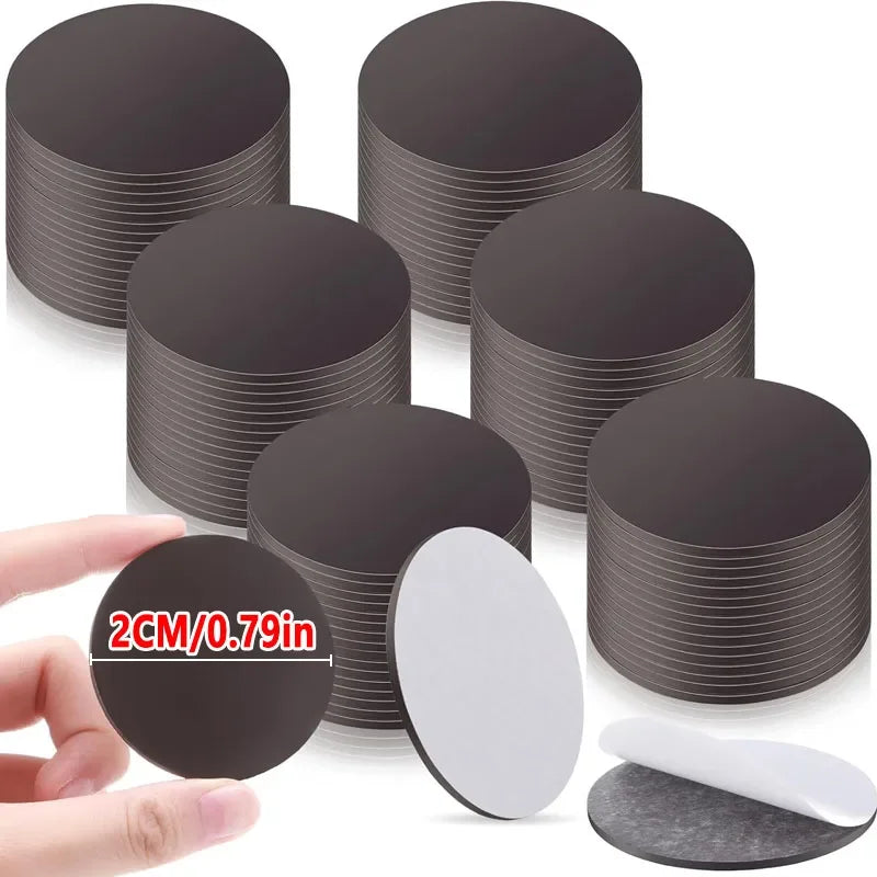 Una colección de puntos magnéticos redondos y autoadhesivos en blanco y negro sostenidos por una mano.