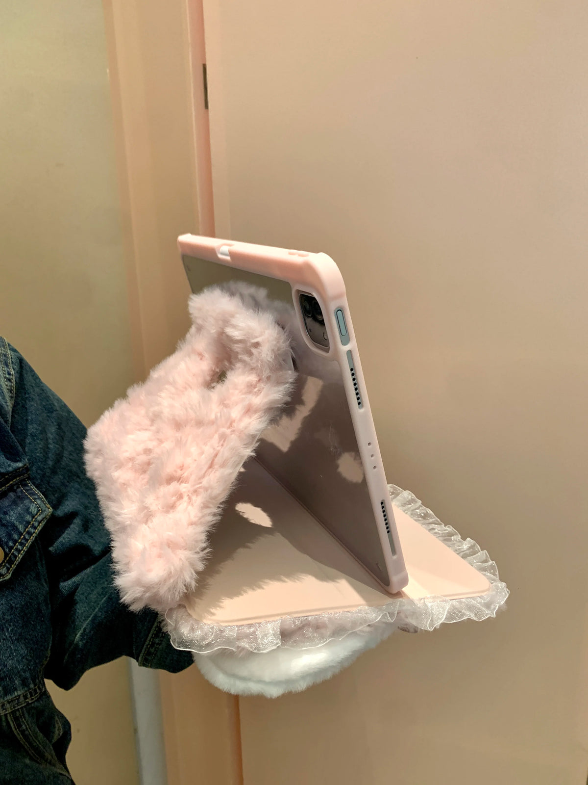 A pink rabbit plush case is shown resting on a light pink iPad, next to a denim jacket.
