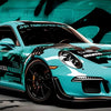 A turquoise JDM car is featured in a dynamic, low-angle shot against a dark background.